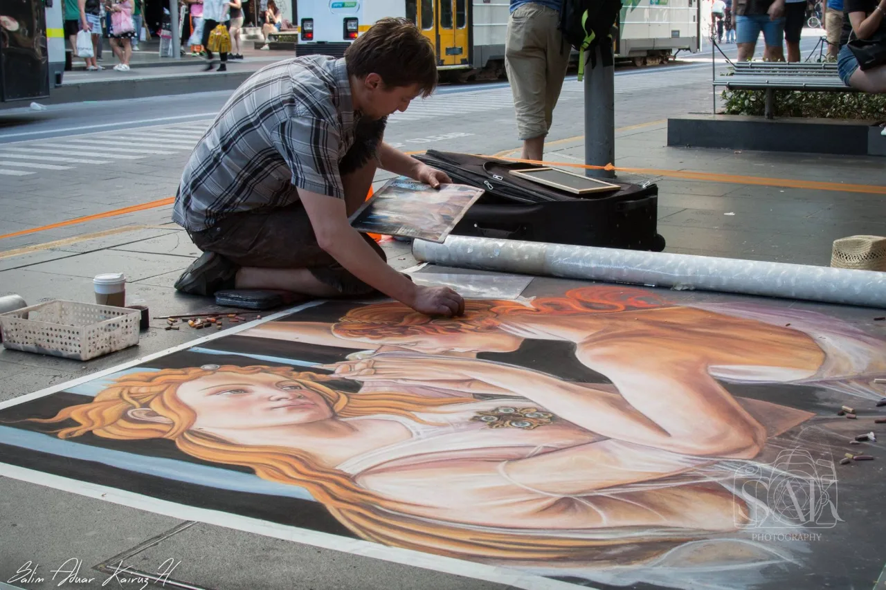 Street artist drawing a chalk portrait on the pavement