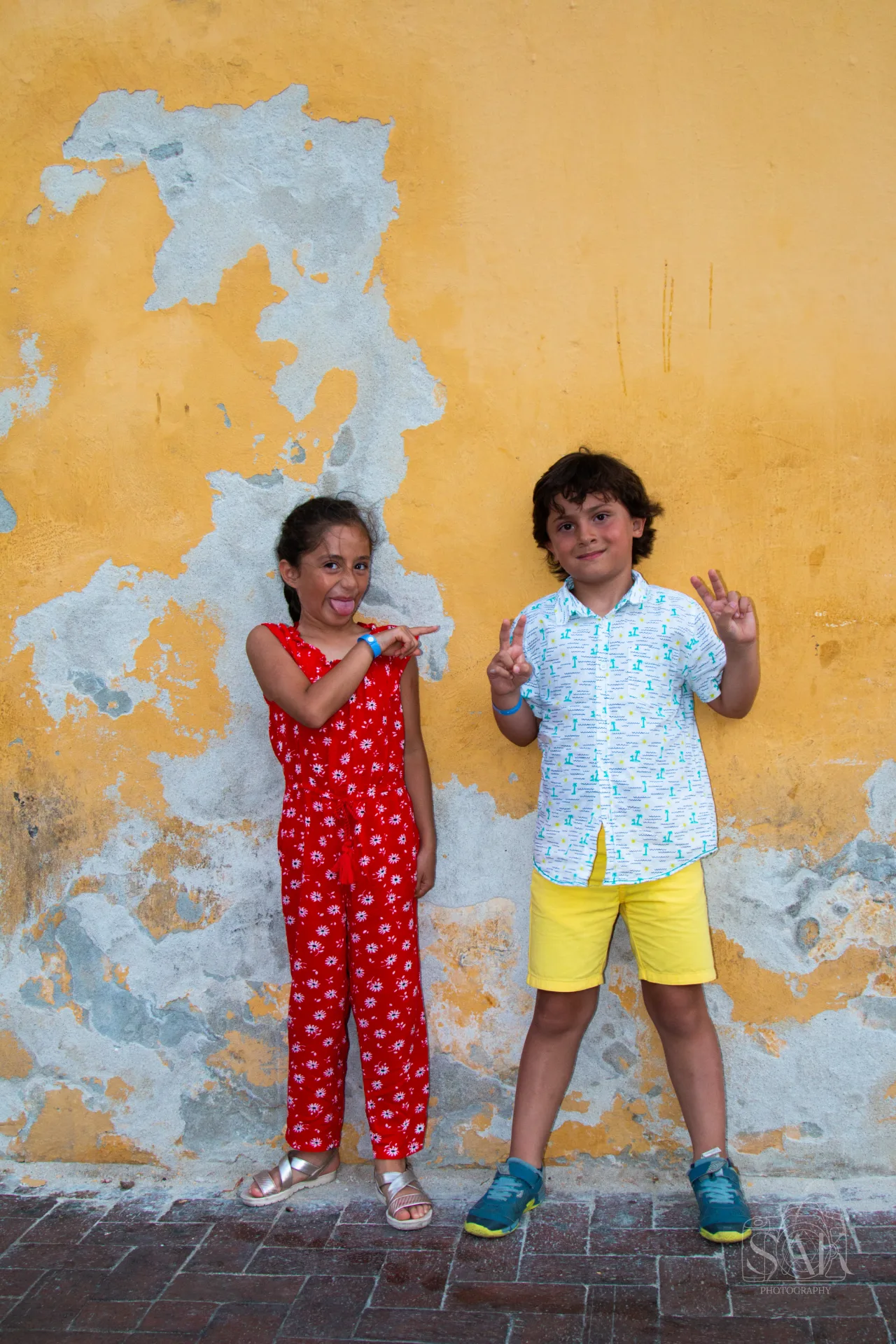 Dos niños frente a un muro amarillo desgastado en Cartagena